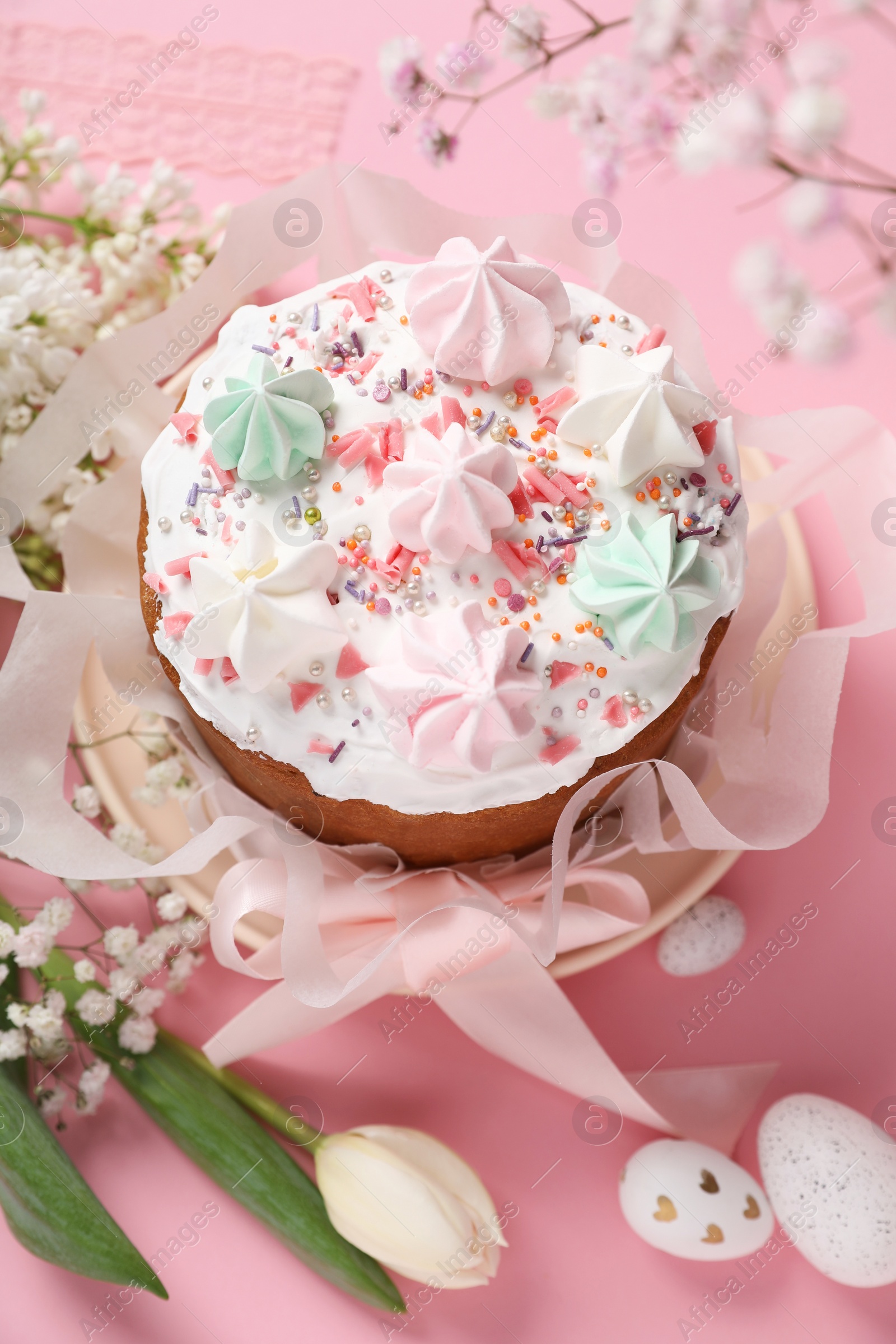 Photo of Traditional Easter cake with meringues and painted eggs on pink background, above view