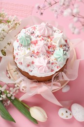 Photo of Traditional Easter cake with meringues and painted eggs on pink background, above view