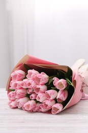 Beautiful bouquet of fresh pink tulips on white wooden table indoors