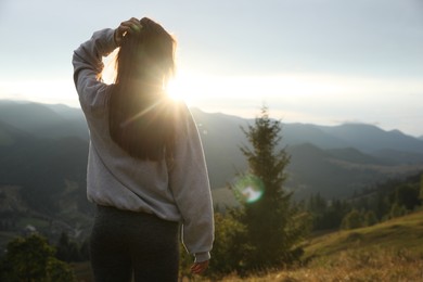 Photo of Beautiful young woman enjoying her time in mountains, back view. Space for text