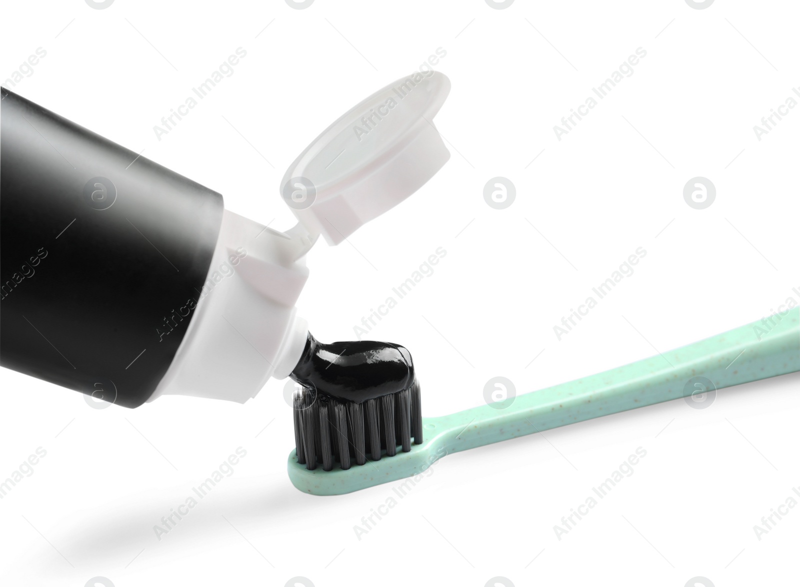 Photo of Tube of charcoal toothpaste and brush on white background