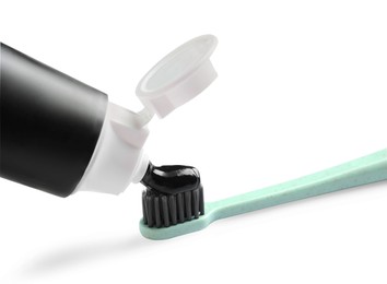Tube of charcoal toothpaste and brush on white background