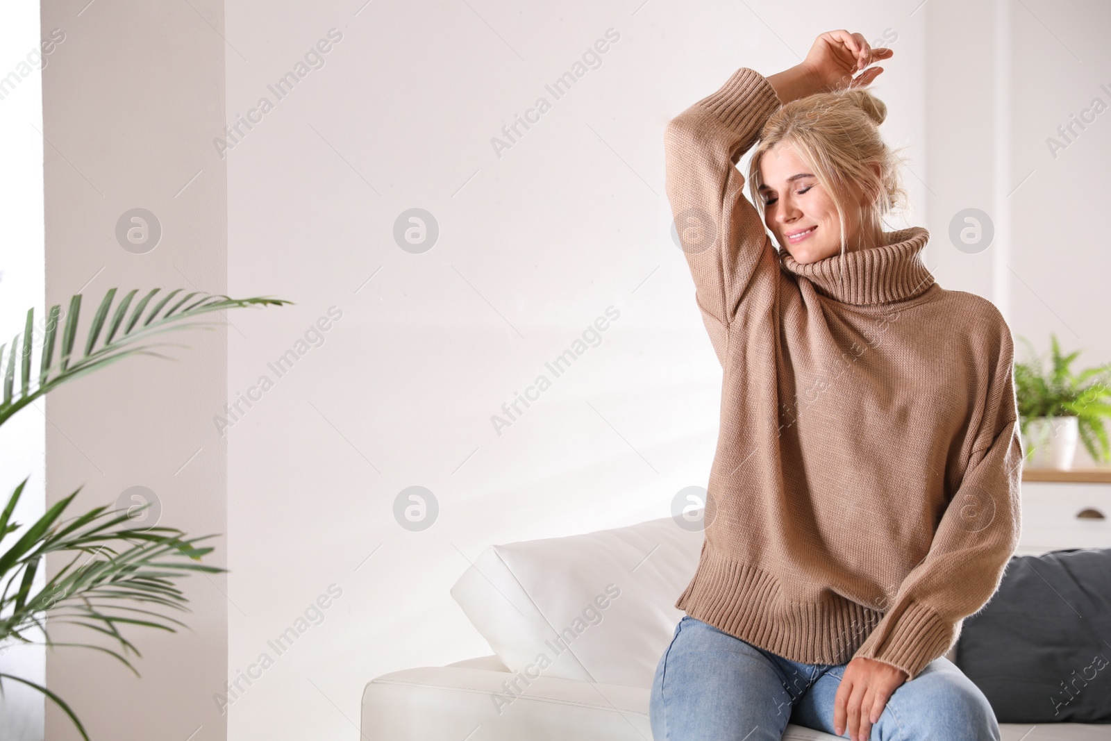 Photo of Happy woman in stylish sweater in light room