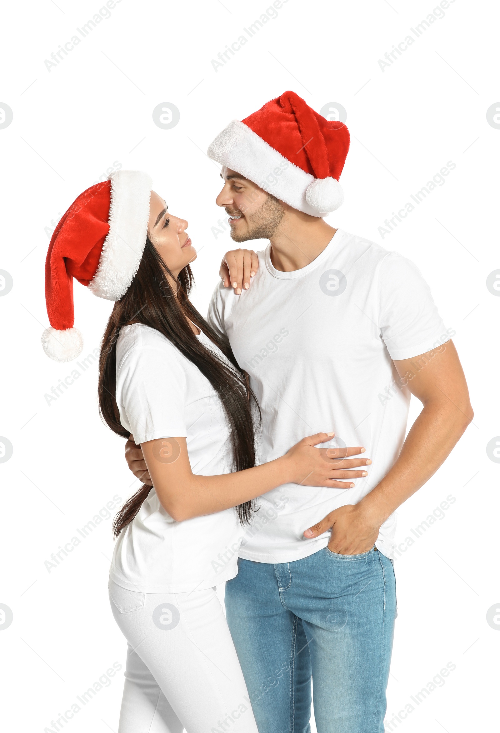 Photo of Young happy couple with Santa hats on white background. Christmas celebration