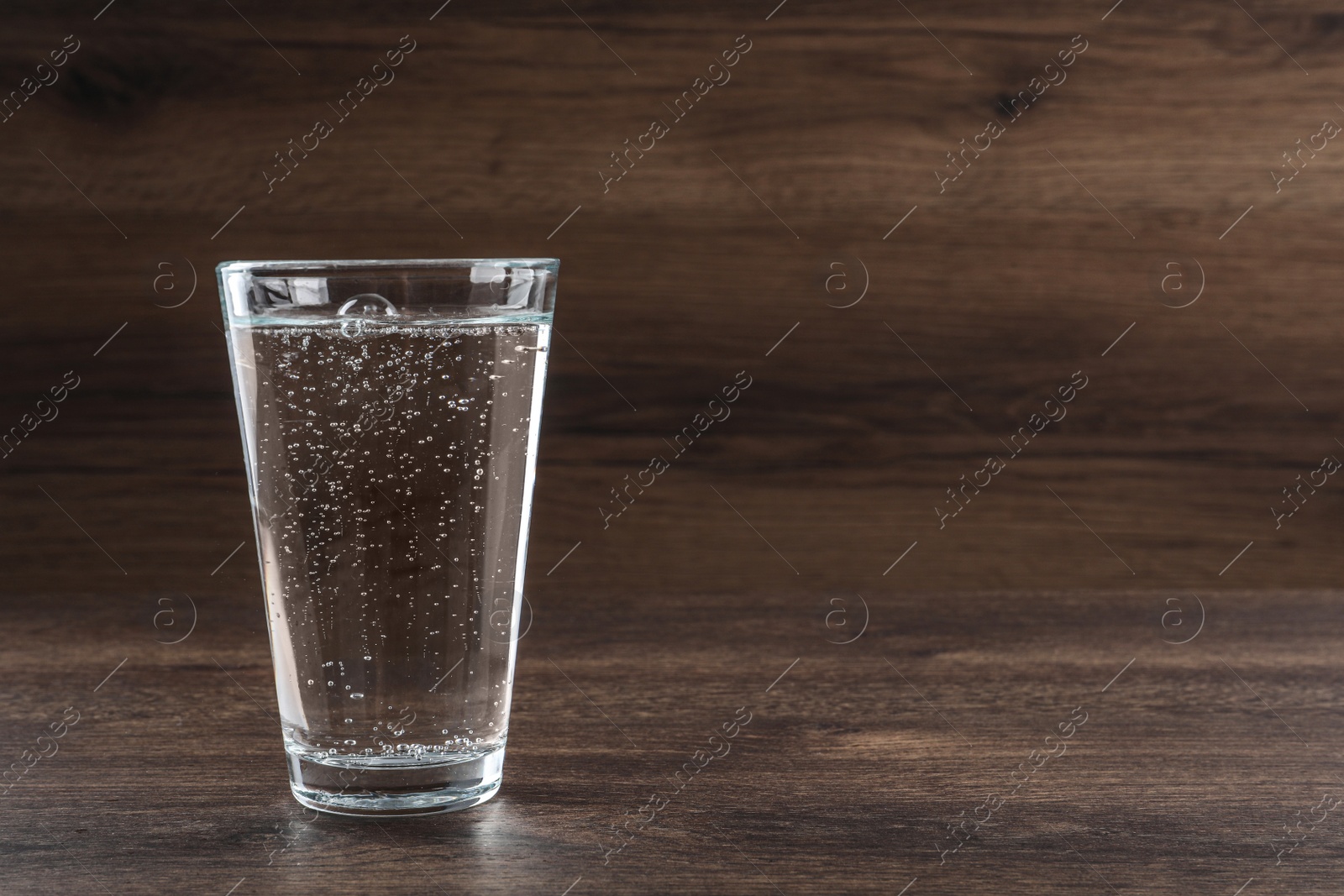 Photo of Glass of soda water on wooden table. Space for text