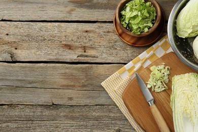 Photo of Fresh Chinese cabbages and knife on wooden table, top view. Space for text