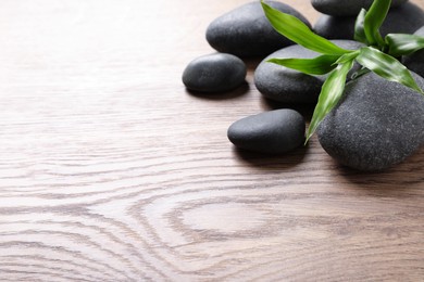 Photo of Spa stones and bamboo sprout on wooden table, space for text