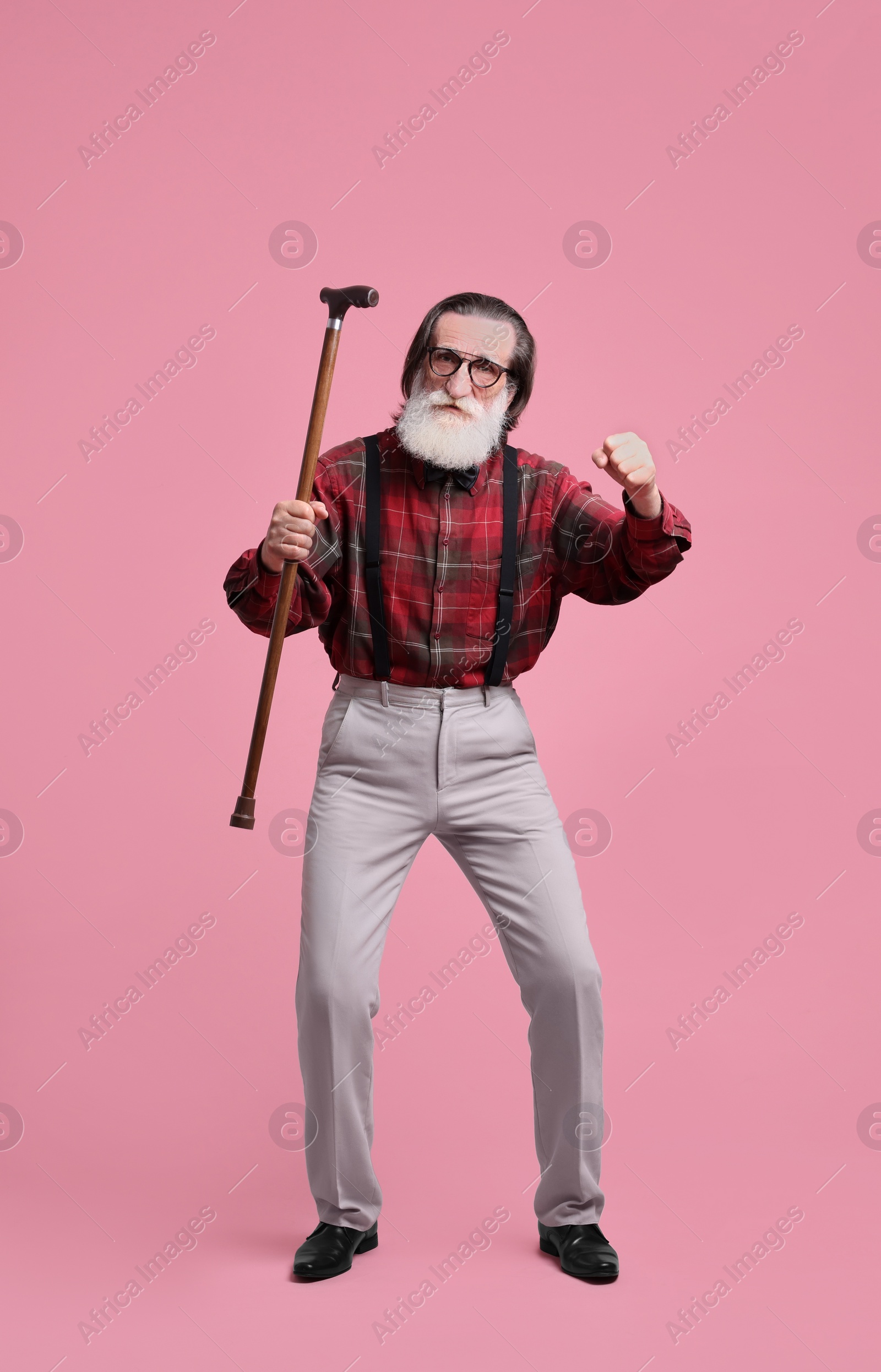 Photo of Senior man with walking cane on pink background