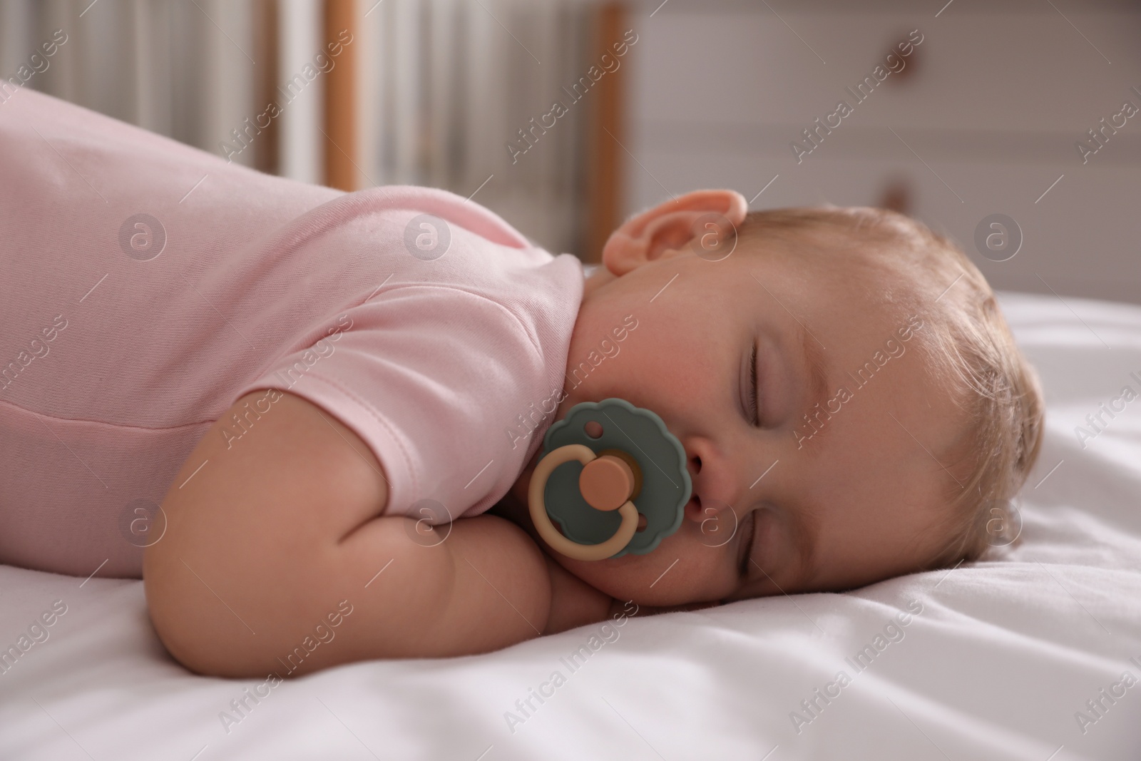 Photo of Adorable little baby with pacifier sleeping on bed at home