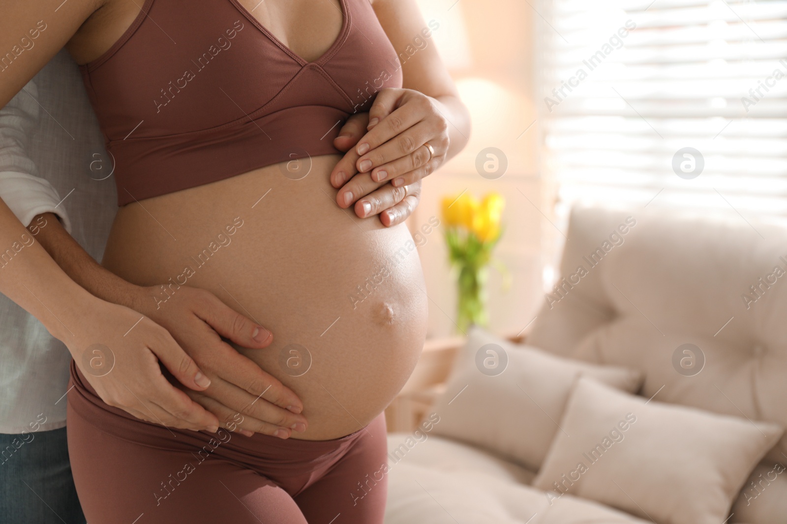 Photo of Man touching his pregnant wife's belly at home, closeup. space for text