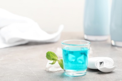 Photo of Glass with mouthwash on marble table. Teeth care