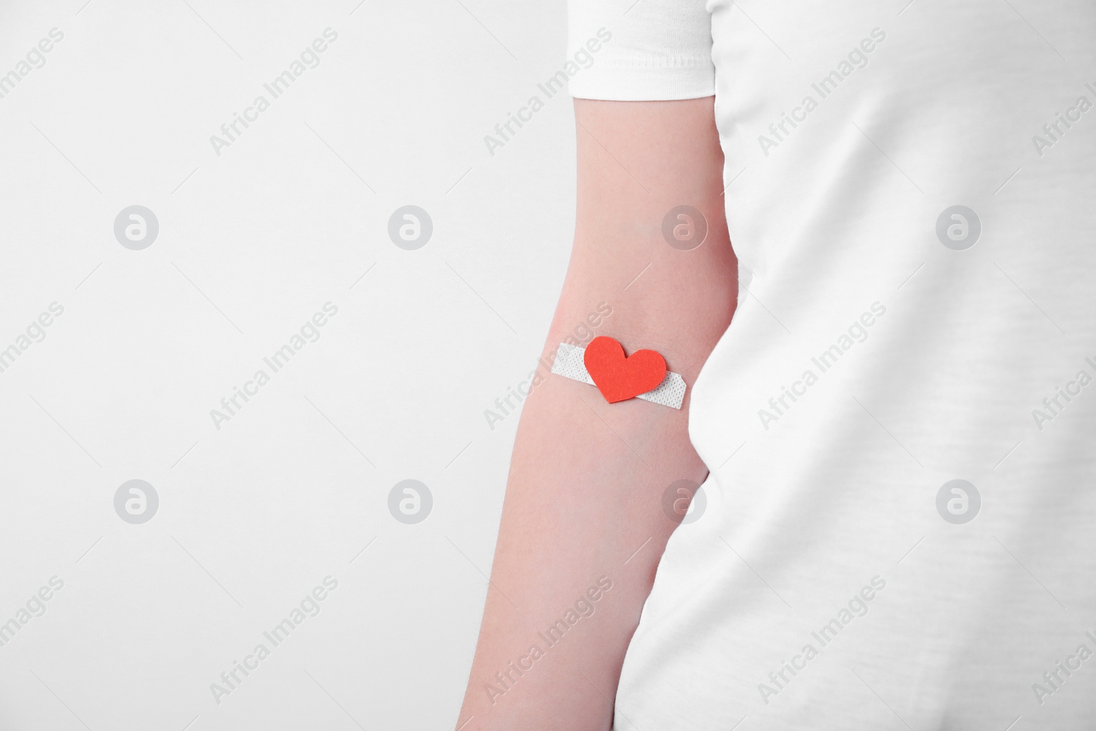 Photo of Blood donation concept. Woman with adhesive plaster on arm against white background, closeup. Space for text