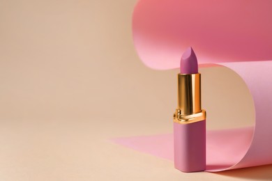 Photo of Beautiful lipstick on beige background, space for text. Professional makeup product