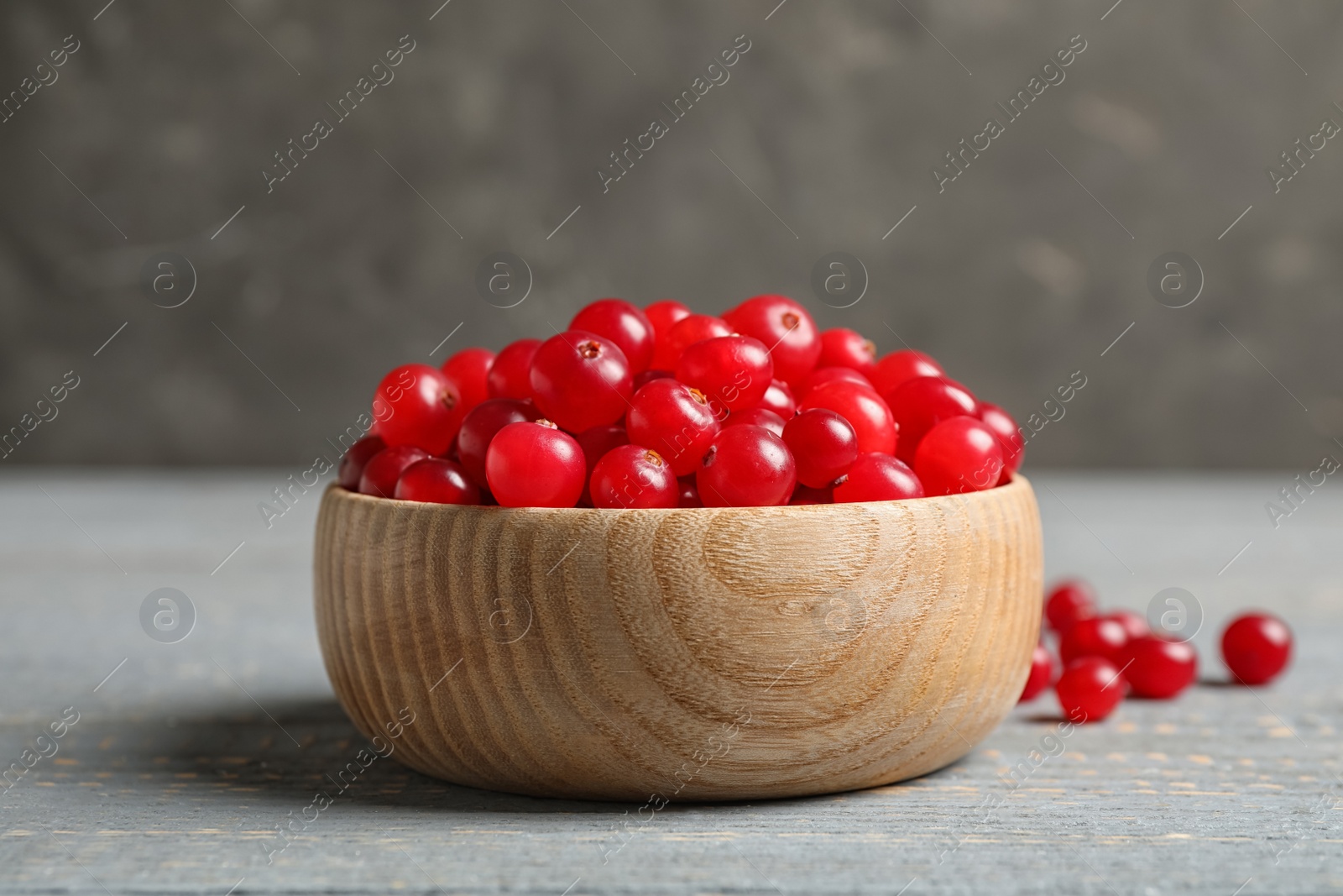 Photo of Tasty ripe cranberries on grey wooden table, closeup