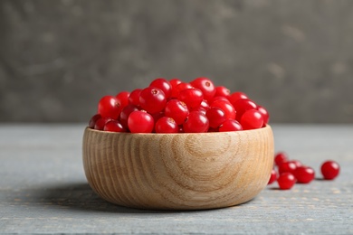 Tasty ripe cranberries on grey wooden table, closeup