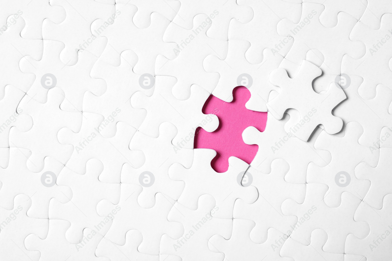 Photo of Blank white puzzle with separated piece on pink background, top view. Space for text