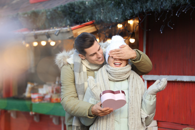 Photo of Man presenting Christmas gift to his girlfriend at winter fair
