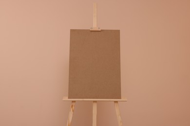 Wooden easel with blank board on beige background