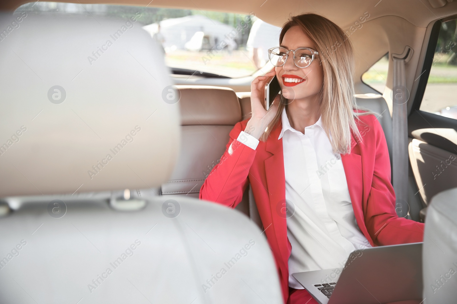 Photo of Young businesswoman with smartphone and laptop in car