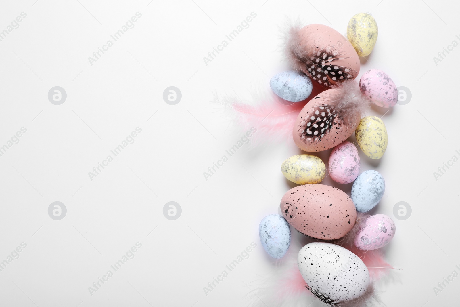 Photo of Many painted Easter eggs with feathers on white background, flat lay. Space for text