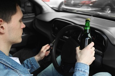 Man with bottle of beer driving car, closeup. Don't drink and drive concept