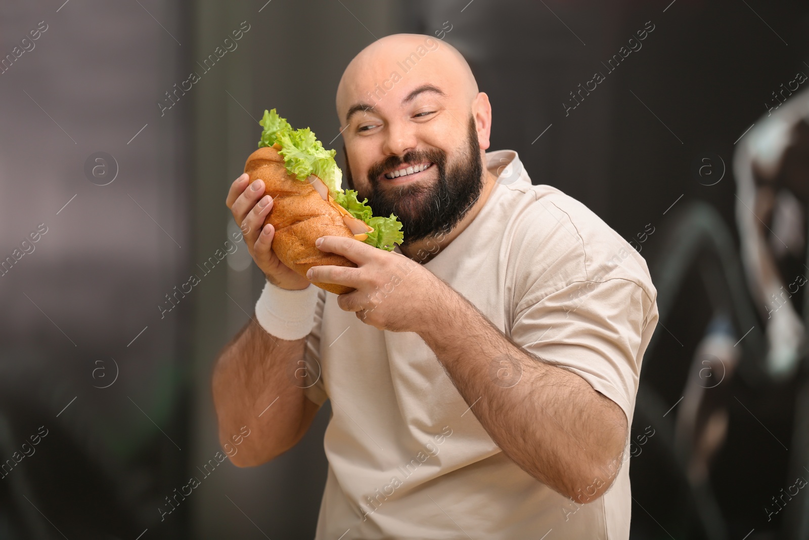 Photo of Overweight man eating sandwich in gym