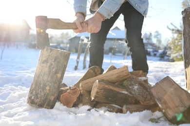 Man chopping wood with axe outdoors on winter day, closeup