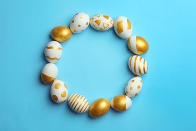 Frame made of traditional Easter eggs decorated with golden paint on color background, top view. Space for text