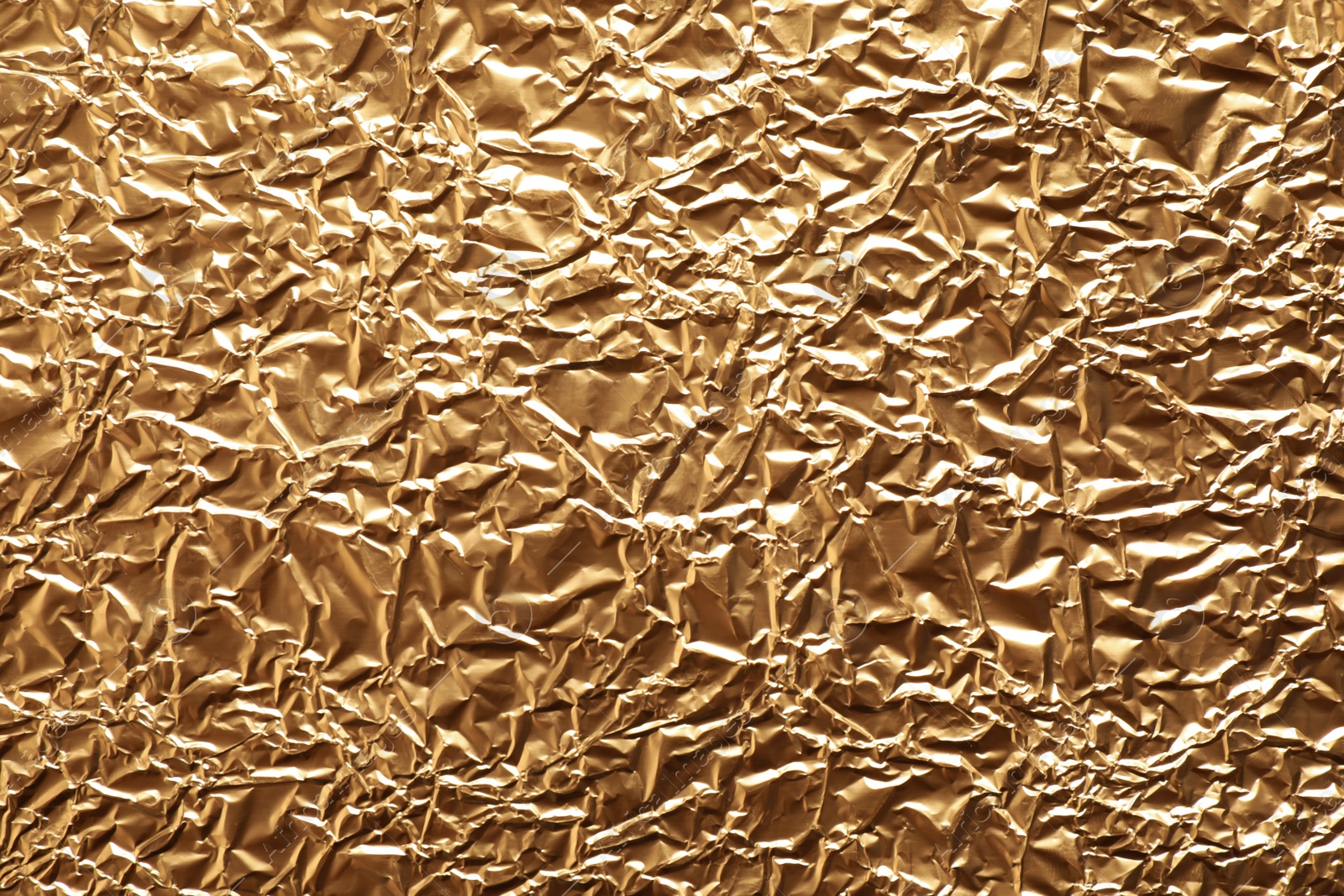 Photo of Crumpled gold foil as background, top view