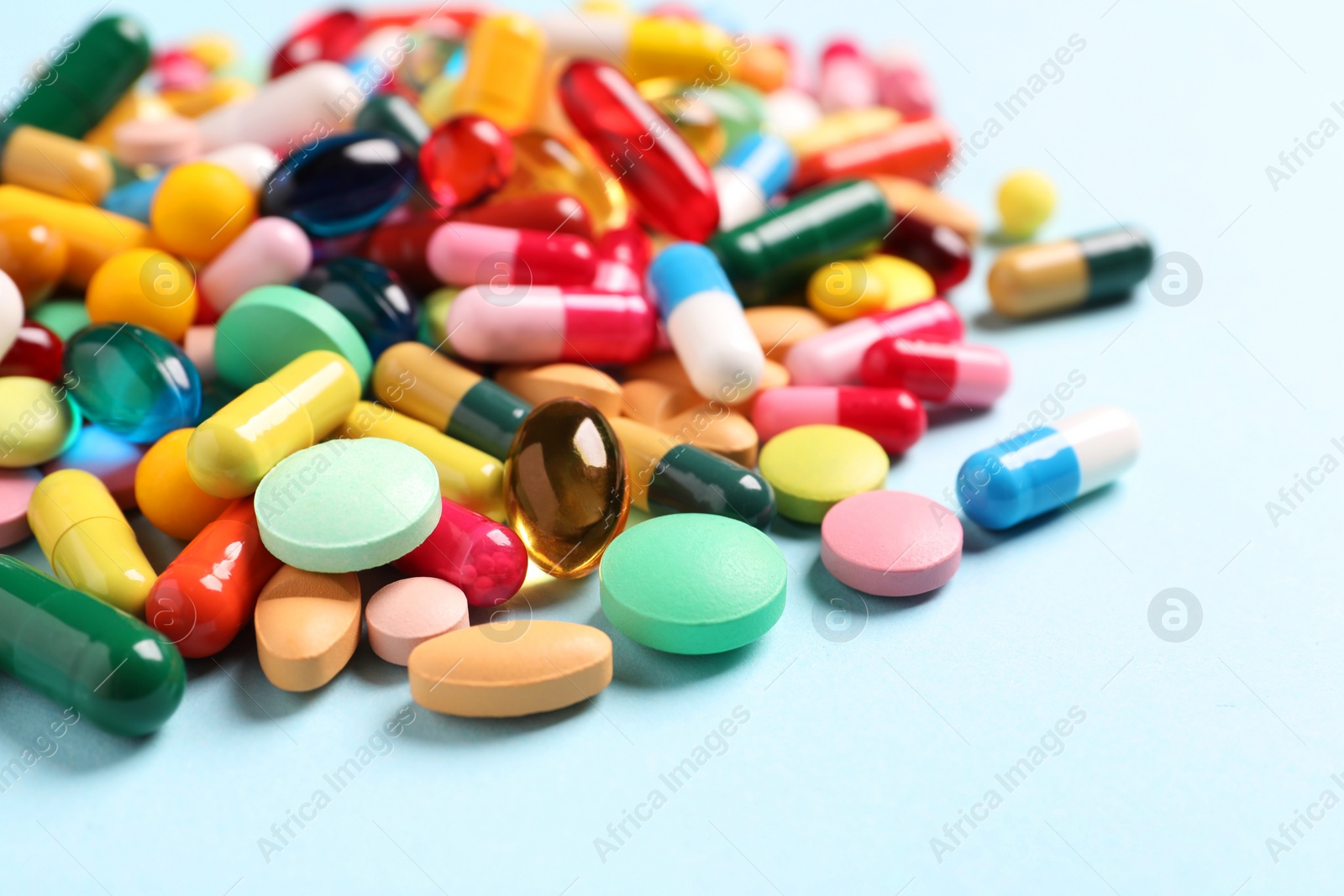 Photo of Many different pills on light blue background, closeup. Space for text