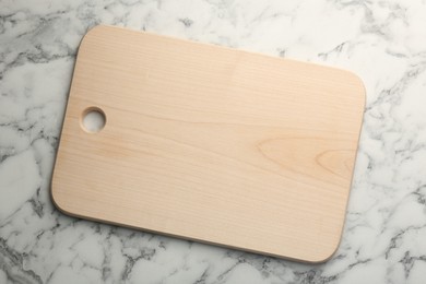 Wooden cutting board on white marble table, top view. Space for text