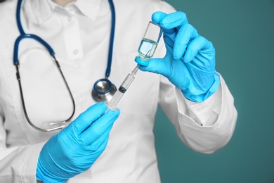 Doctor with syringe and medicine for vaccination on color background