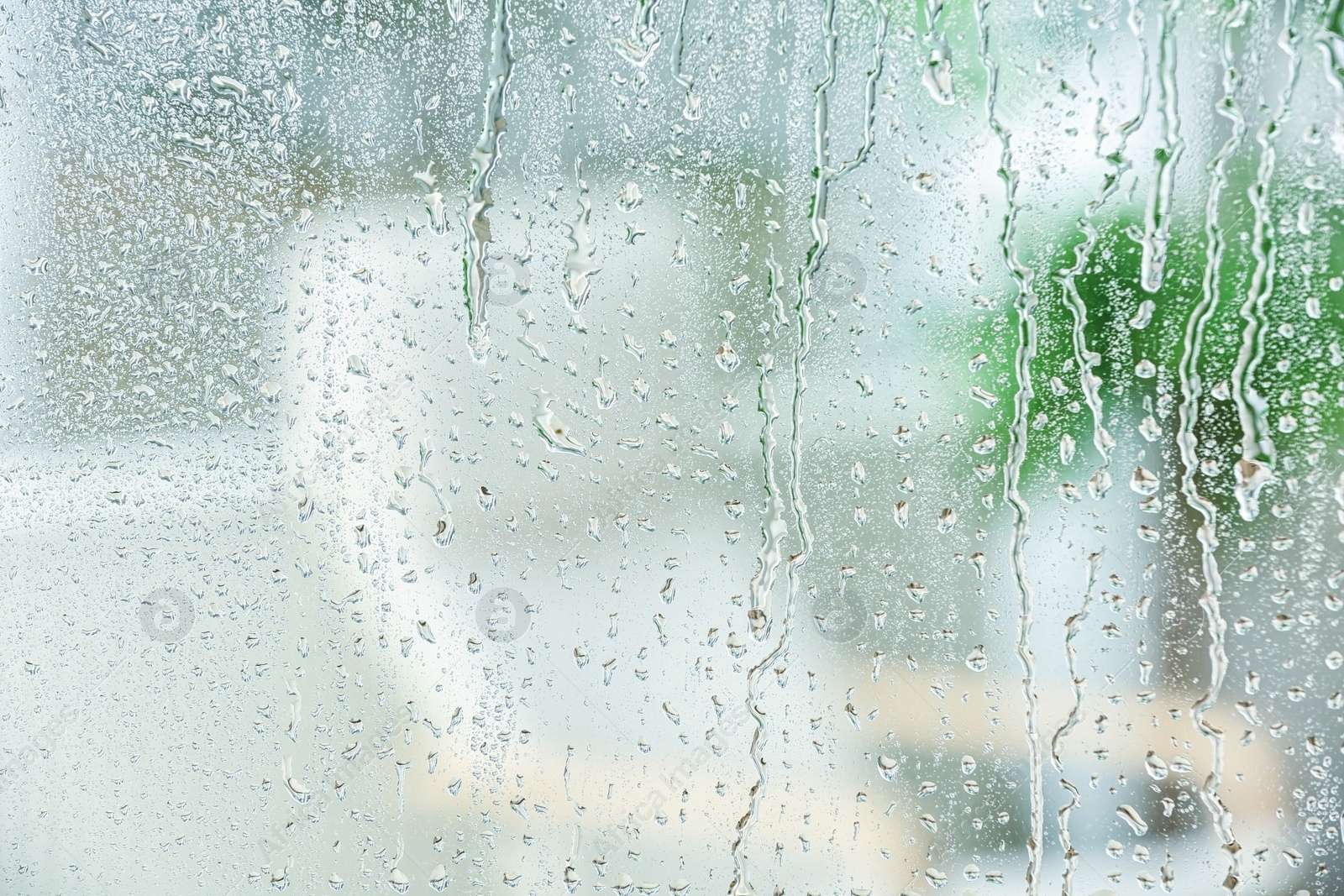Photo of Blurred view of room through glass with water drops, closeup