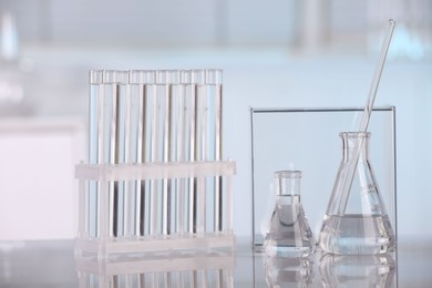 Photo of Laboratory analysis. Glass flasks, test tubes and stirring rod on white table indoors