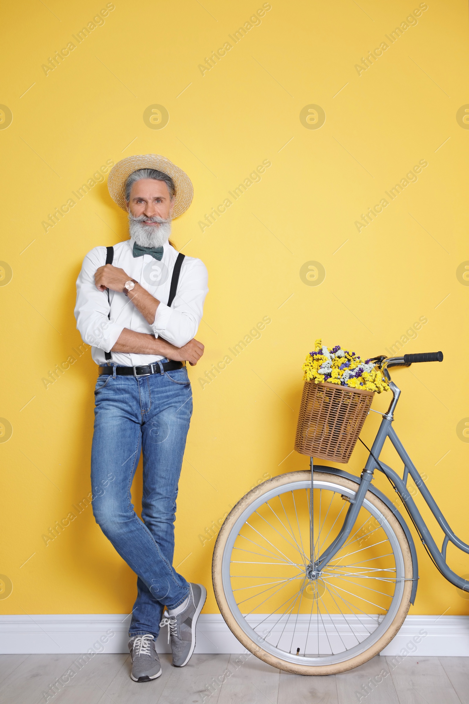 Photo of Portrait of handsome mature man with bicycle near color wall