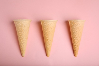 Photo of Empty wafer ice cream cones on pink background, flat lay