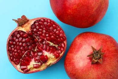 Whole and cut fresh pomegranates on light blue background, flat lay