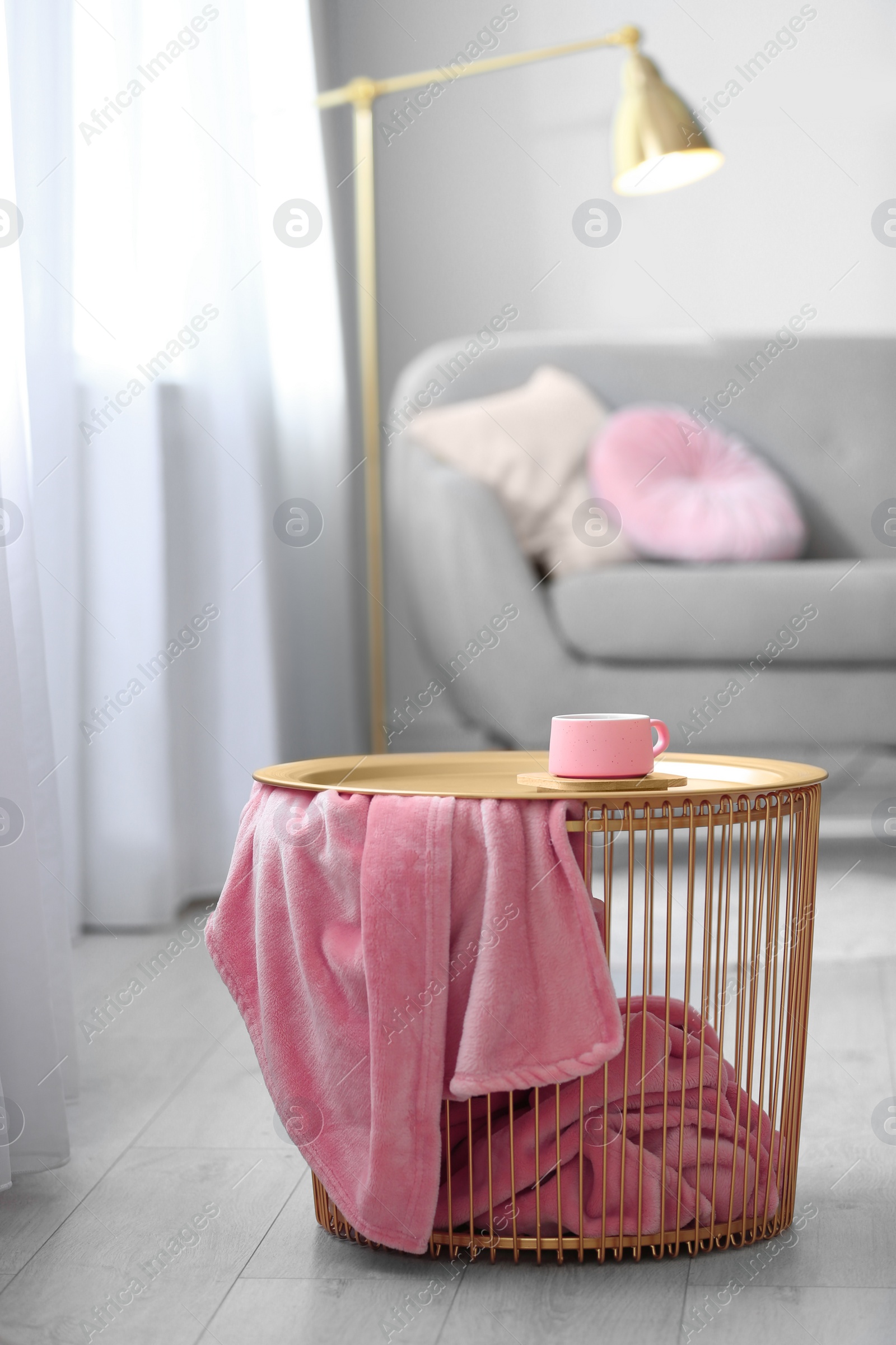 Photo of Side basket table with cup of coffee and blanket in modern room interior