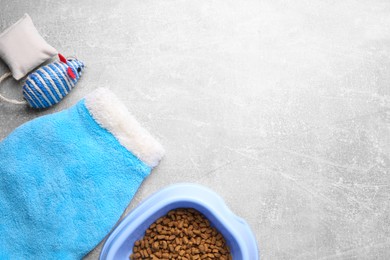 Flat lay composition with cat clothes, food and accessories on grey table. Space for text