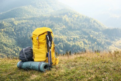 Photo of Backpack, trekking poles and sleeping mat in mountains, space for text. Tourism equipment