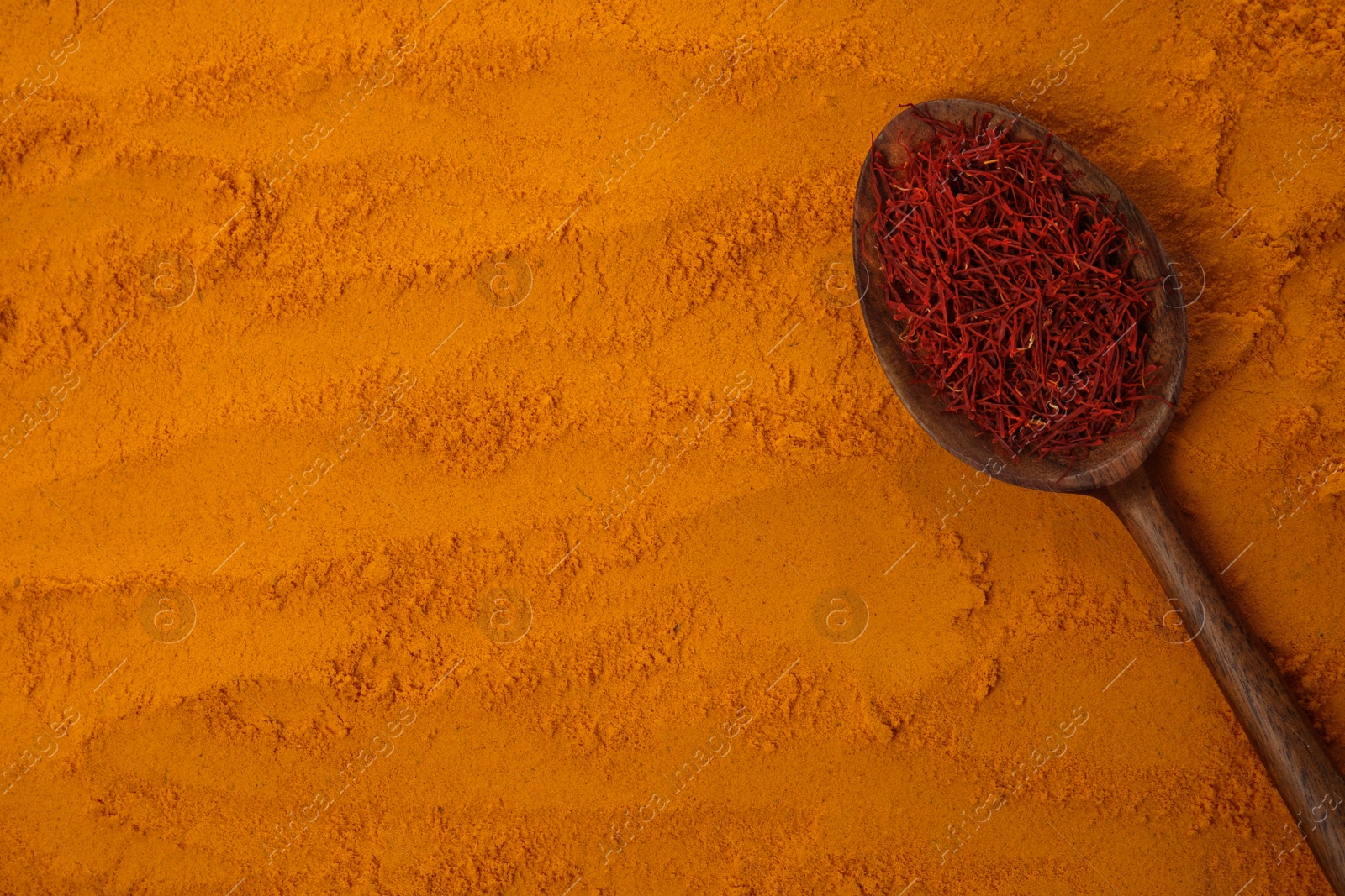 Photo of Spoon of dried flower stigmas on saffron powder, top view. Space for text