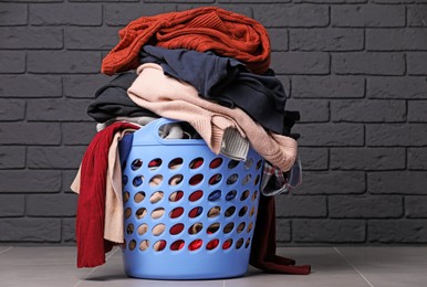 Photo of Laundry basket with clothes near black brick wall