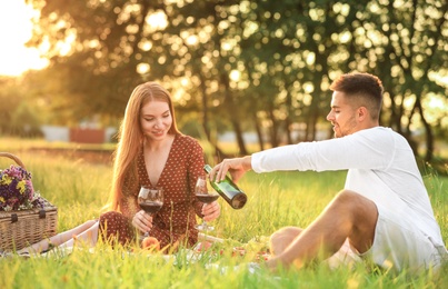 Photo of Young man and his girlfriend having picnic in green park