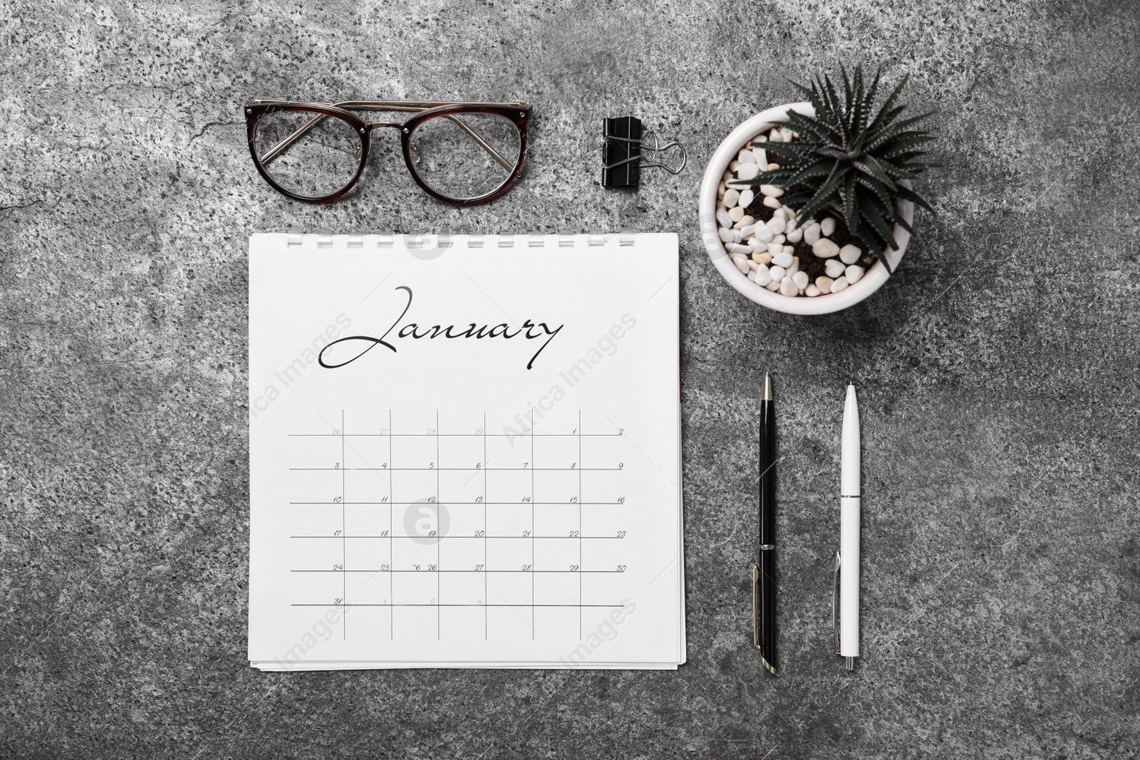 Photo of Flat lay composition with calendar and succulent on grey stone table