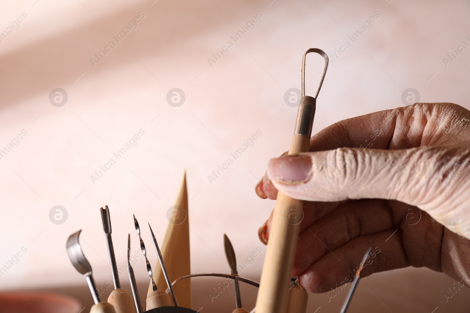 Photo of Woman with clay crafting tool in workshop, closeup. Space for text