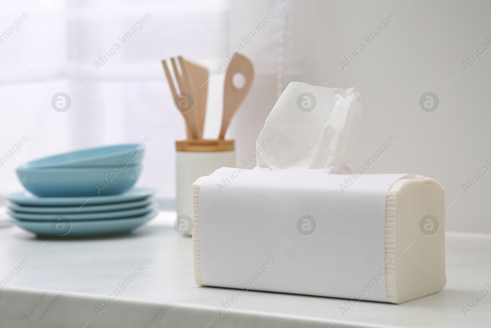 Photo of Package of paper towels on white countertop in kitchen. Space for text