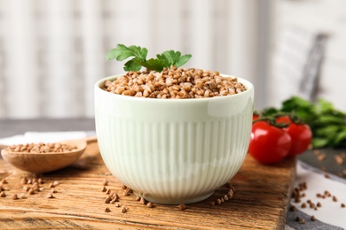 Board with bowl of buckwheat porridge on table