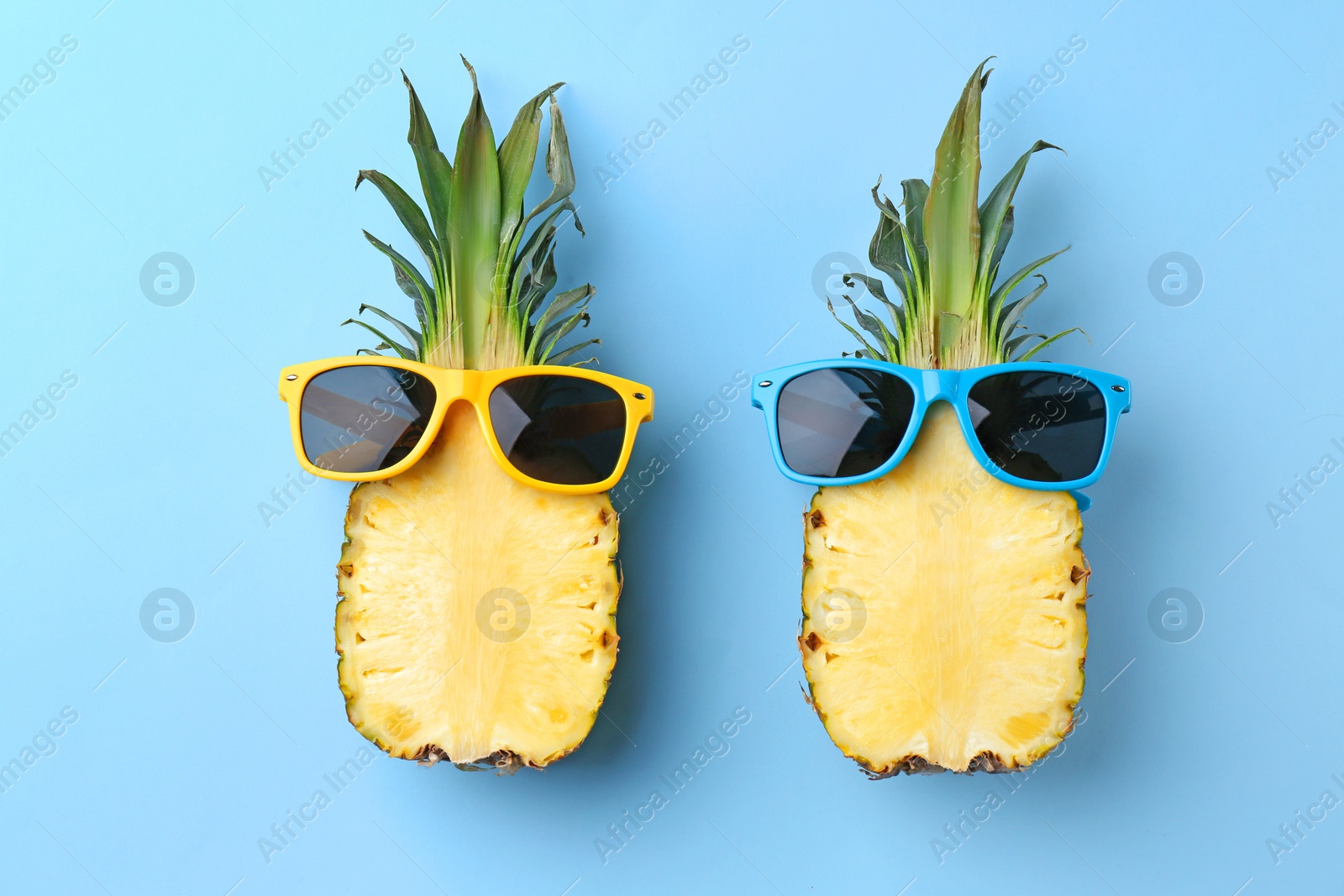 Photo of Funny pineapples with sunglasses on color background