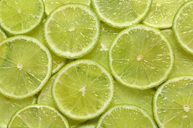 Photo of Juicy lime slices as background, top view. Citrus fruit