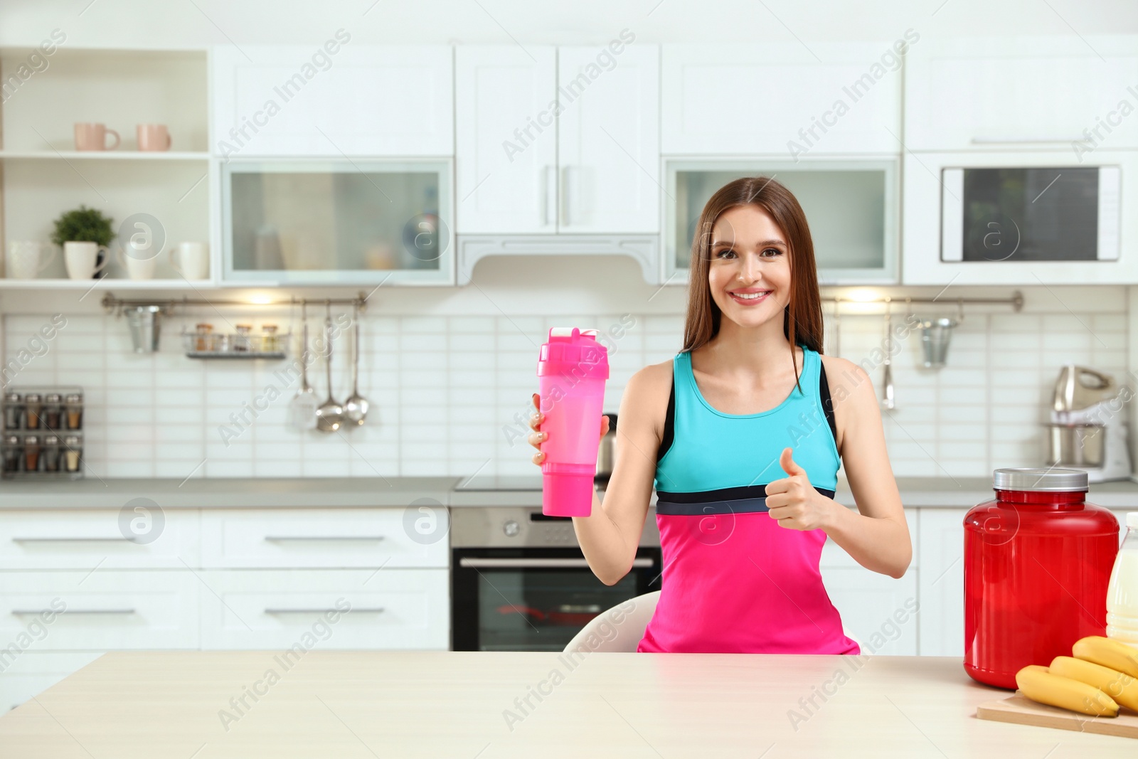 Photo of Young woman with bottle of protein shake in kitchen